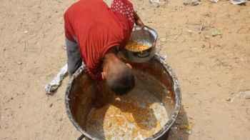 A heartbreaking image… he collects leftover food after a long wait.