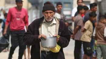 Heavy steps burdened by war.. an elderly man carries a survival meal for his family in Gaza